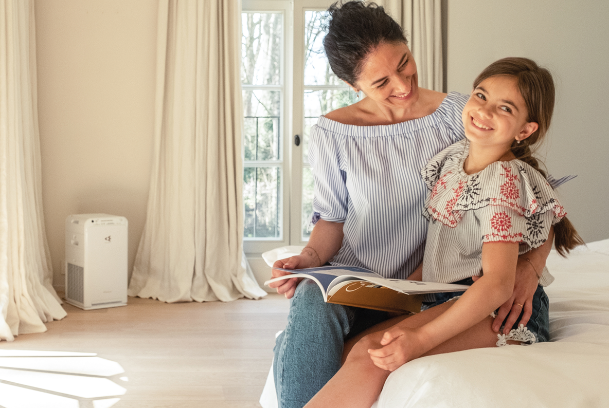 Mother and child at home with air purifier reducing indoor allergens and improving air quality